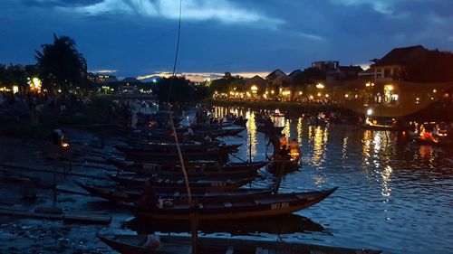 Boats moored at illuminated shore against sky at night