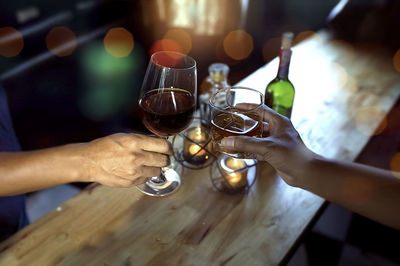 Midsection of man holding wine glass on table