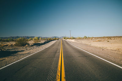 Road passing through landscape against clear sky