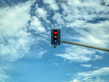 Low angle view of road signal against blue sky with swirling white clouds and copy space.