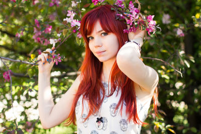 Portrait of beautiful young woman standing against tree