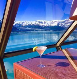 Drink on table by window against sea