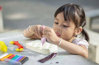 Close-up of cute girl playing with childs play clay at table outdoors