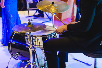 Midsection of man playing drums at music concert