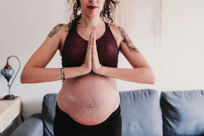 Midsection of pregnant woman exercising at home