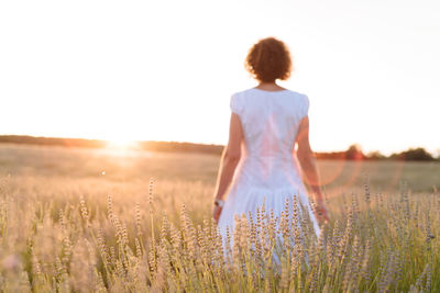 Rear view of woman standing on field against clear sky