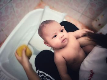 Midsection of woman bathing newborn son in bathroom