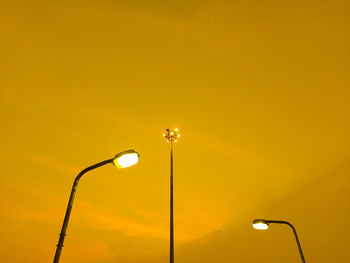 Low angle view of illuminated street light against orange sky