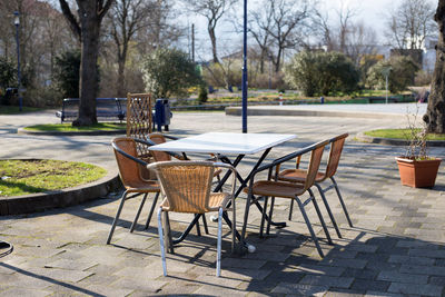 Wicker stack chairs or garden chairs at an outdoor table in sunny weather