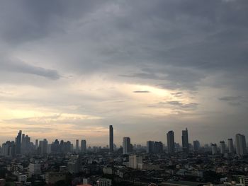 Modern buildings in city against sky during sunset