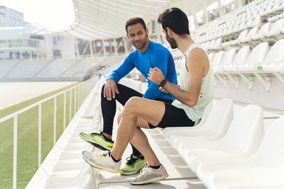 Side view of young man sitting on railing