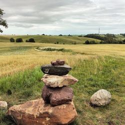 Stack of stones on field against sky