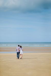 Rear view of man and woman walking on beach