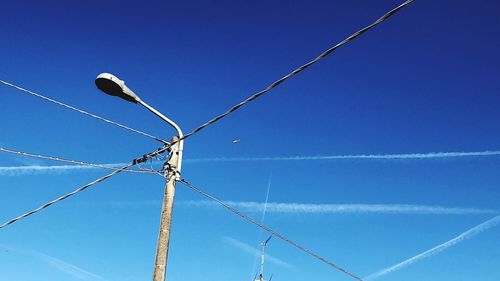 Low angle view of power lines against clear blue sky