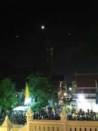 Crowd on illuminated city against sky at night