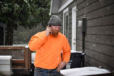 Midsection of man using phone on snowy day