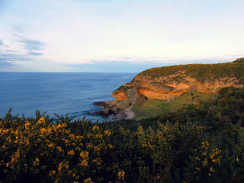 Scenic view of sea by cliff against sky