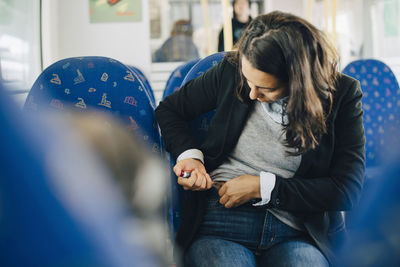 Woman injecting in abdomen while sitting by window in train