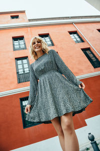 Portrait of woman standing against building in city