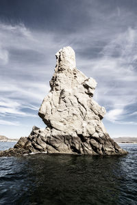 Rock formation in sea against sky