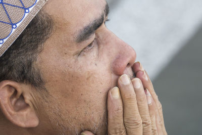 Close-up of mature man praying while sitting at mosque