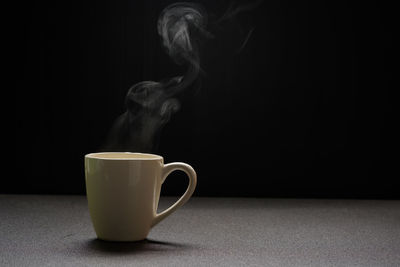 Close-up of coffee cup on table against black background