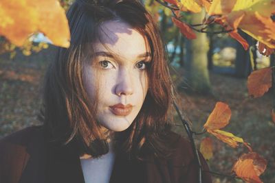 Close-up portrait of young woman amidst autumn leaves