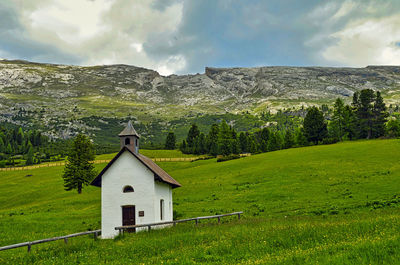 Built structure on field by buildings against sky