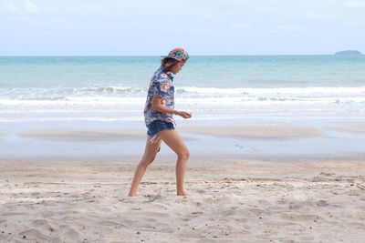 Full length of woman walking on beach against sky