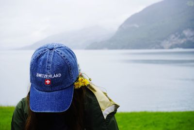 Close-up of young woman wearing cap while looking down at lake