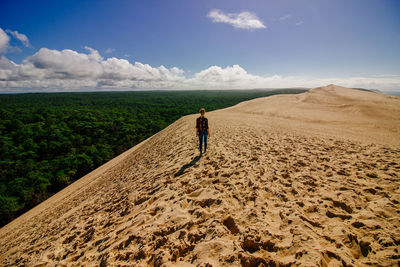 Rear view of man standing on sand against sky