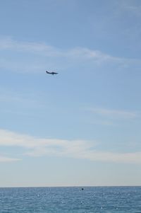 Airplane flying over sea against sky