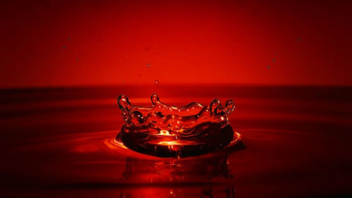 Close-up of water splashing against red background