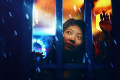 Portrait of woman looking through window