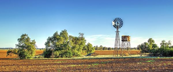 Windmill on field against blue sky