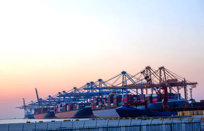 Cranes at commercial dock against sky