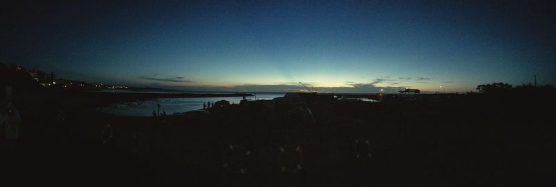 Scenic view of beach against clear sky at sunset