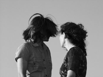 Women with tousled hair standing against gray background