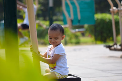 Cute girl sitting on outdoor play equipment