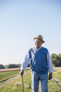 Senior man with a walking stick, walking in the fields