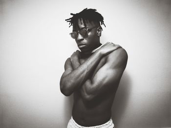 Full length of shirtless man standing against wall