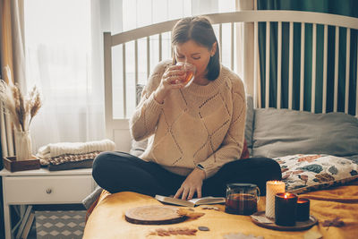 Young woman sitting on bed at home