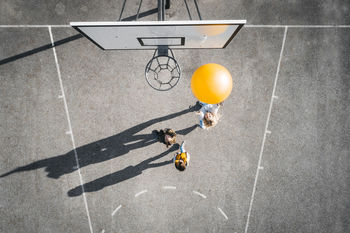 Austria, aerial view of basketball field, mother and children playing basketball with big ball