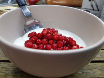Close-up of red fruits and yogurt in bowl on table