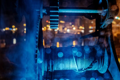 Close-up of pulley against illuminated lights at night