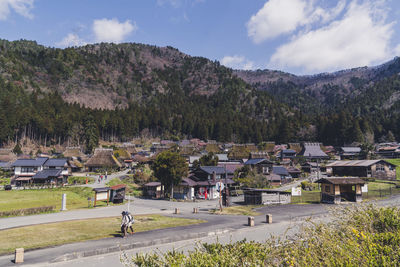 Trees and houses by road against sky