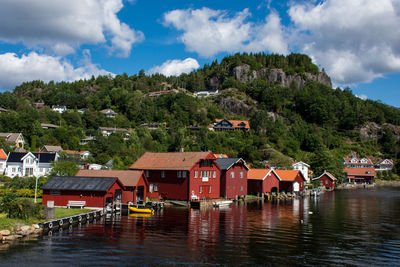 Houses by lake and buildings against sky