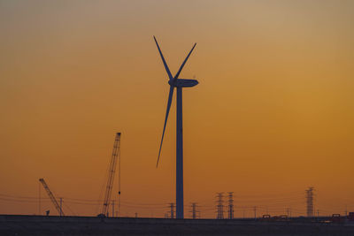 Low angle view of silhouette wind turbine against sky during sunset