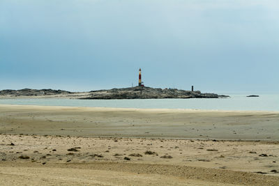 Lighthouse on beach against clear sky