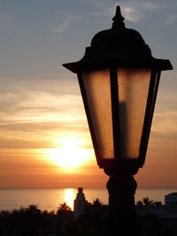 Silhouette built structure against sea during sunset